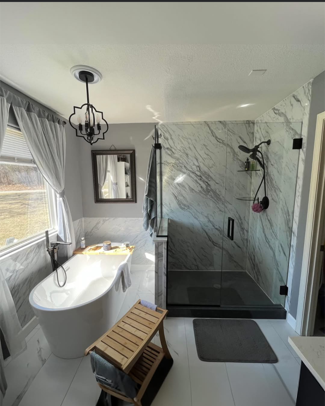 Luxury master bathroom remodel with freestanding tub, walk-in glass shower, and marble tile walls